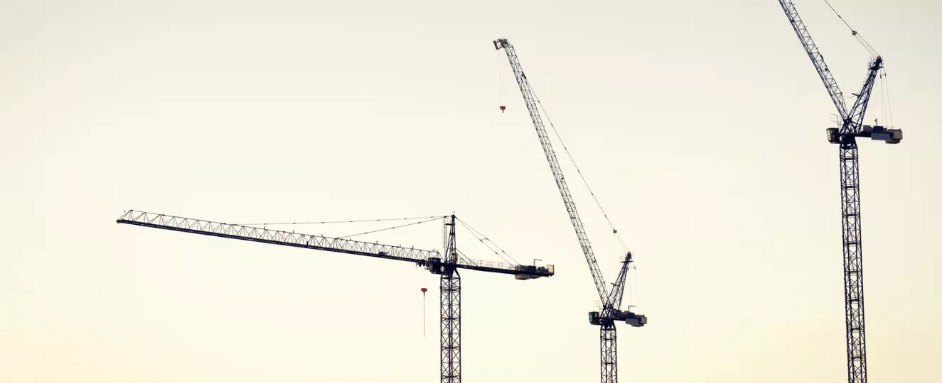Three tower cranes with the sunset in the background